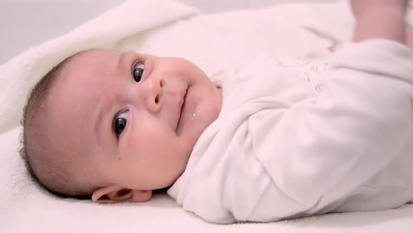 cute tre months old baby boy dressed in white body suit on white baby changer
