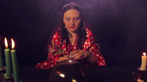 Gypsy fortune teller at the table shuffles fortunetelling cards