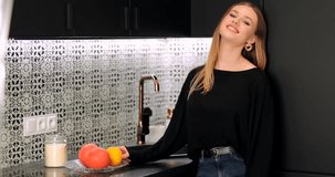 Blonde girl throw nectarine in the kitchen and smile to camera