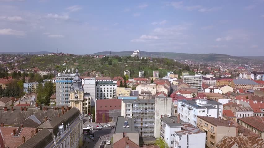 Drone footage slowly flying above the city of Cluj in Romania during a sunny busy day