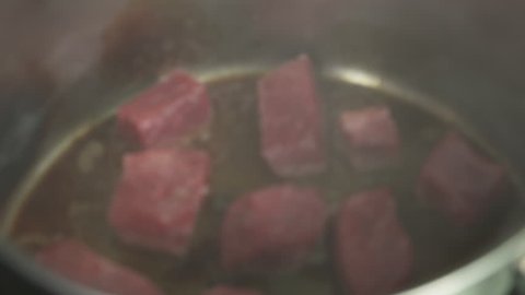 Braising diced beef in a pot before adding to a stew. It's sizzling and looks delicious.