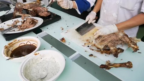Up close video a Chef hands cutting whole grilled lamb for steaks with knife on cutting board. Hot Meat dishes.