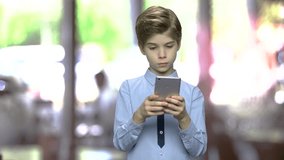 Child boy surfing internet on digital smartphone. Cute caucasian boy watching video on mobile phone. Abstract blurred background.
