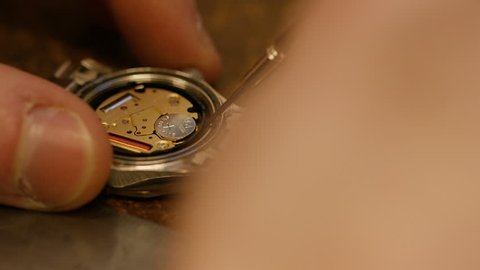 Watch maker removing battery from a wrist watch
