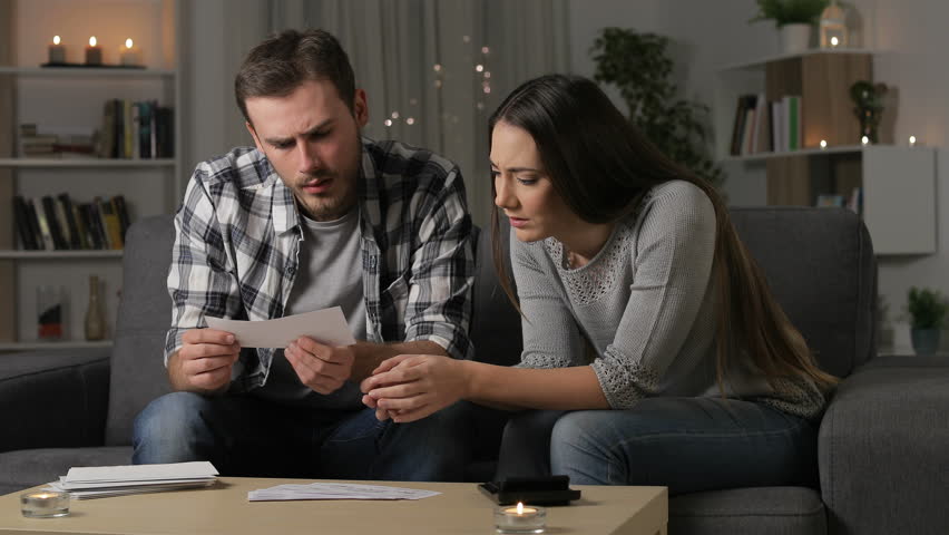 Sad couple checking bank receipts sitting on a couch in the night at home Royalty-Free Stock Footage #1023078337