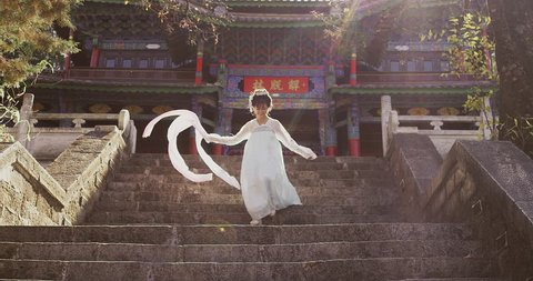 Authentic Asian, beautiful cultural Chinese woman running down steps of ancient building, Yunnan china. Slow motion hand held with sun flare. 