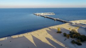Sopot resort in Poland with wooden pier, marina, yachts and sandy beach. Aerial 4K approaching video in sunset light
