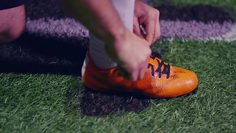 Professional soccer player buckles his boots and enters the field, 4k slow motion
