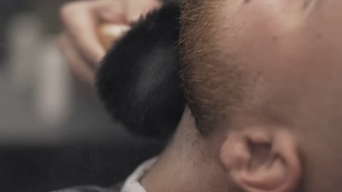 Barber cleaning clients neck with brush at barber shop in slow motion. Close up of hairdresser uses brush with powder to clean customer of cutted hair. Barber shop