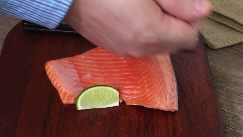 Man put paper around salmon slices on wooden chopper