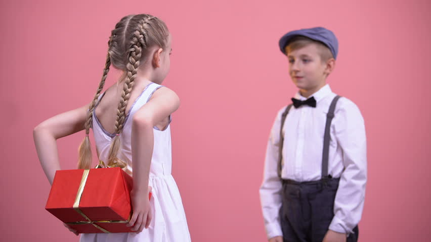 Little girl in white dress giving wrapped present to boyfriend, Valentines day