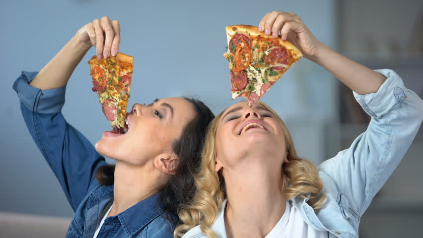 Smiling women greedily eating tasty pizza, fast food addiction, unhealthy diet | Shutterstock HD Video #1023101023
