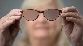Happy aged lady putting on new glasses, visiting ophtalmology clinic, eyesight