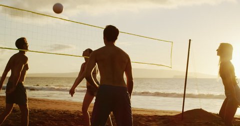 Active friends playing beach volleyball at sunset, slow motion cinematic