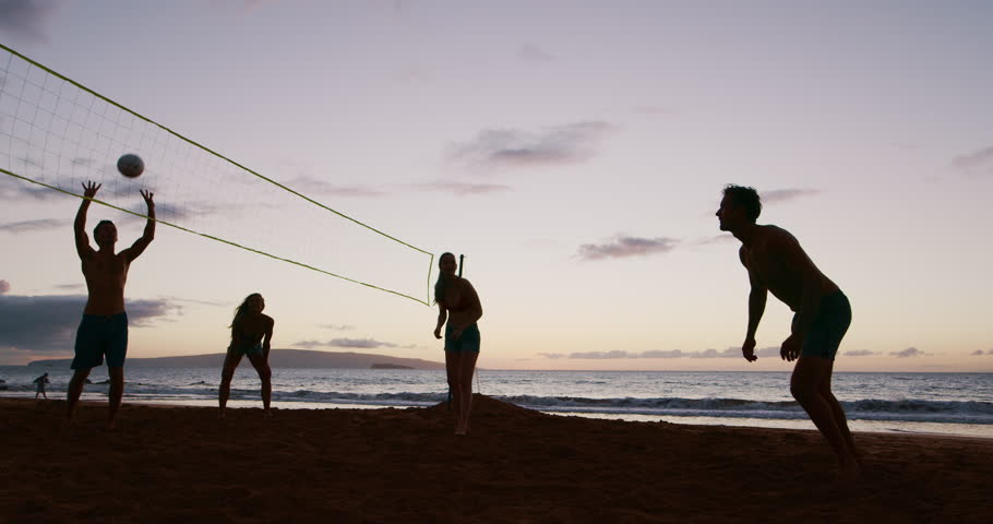 Friends playing beach volleyball at sunset, athletic man dives to save volleyball, cinematic slow motion