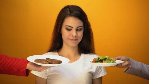 Girl choosing meat instead of salad, rejection of veganism, healthy nutrition