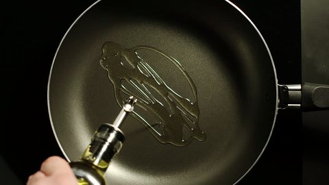 Man pouring cooking oil on the frying pan - Top View