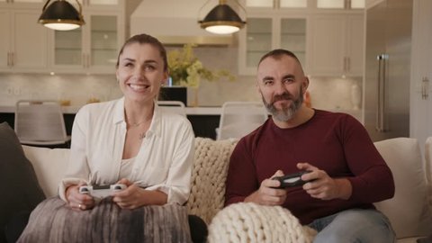 Mid age couple playing video games in cozy modern home / Competition 