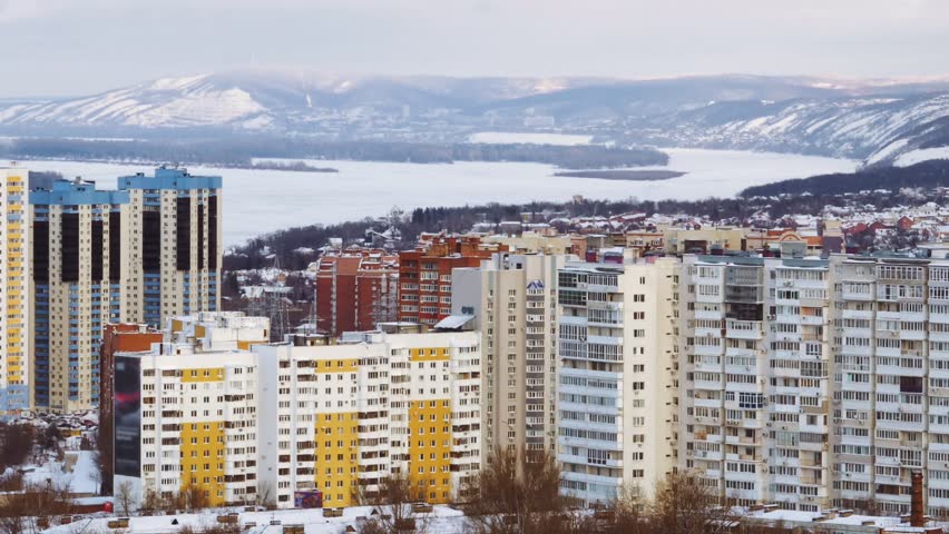 beautiful cityscape with living houses, frozen river and picturesque mountains in winter day