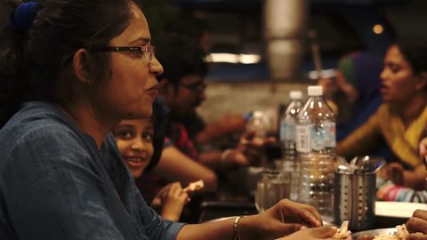 Kuala Lumpur, Malaysia - December 24th, 2018 : Happy Indian family eating together at mamak restaurant at night.