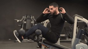 Athletic handsome young man with beard in black sportswear exercising in gym, doing criss cross crunches press exercise. High-intensity interval training. Training concept.