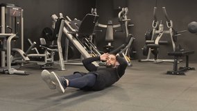 Athletic handsome young man with beard in black sportswear swinging press in gym. Long shot, static shot. Training concept.
