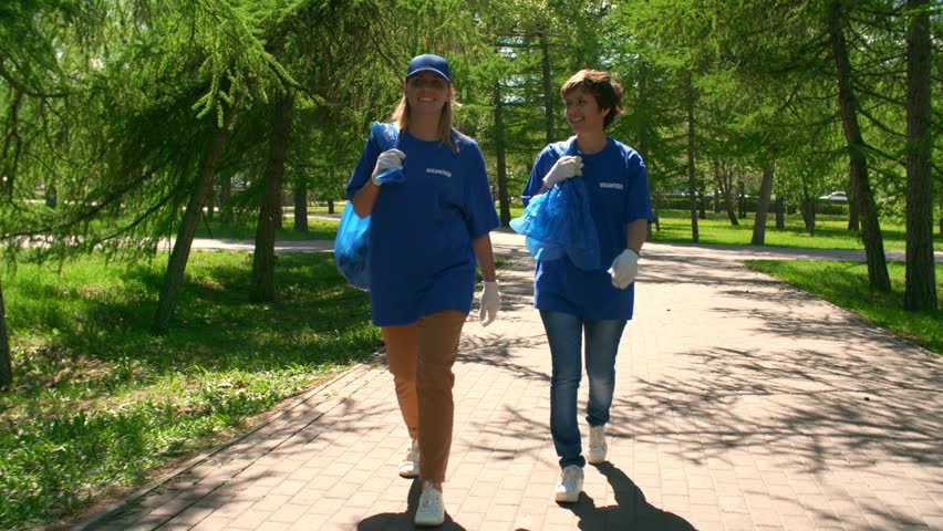 Wide shot of two women in volunteering uniform going somewhere and talking