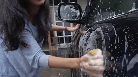 portrait of beautiful young asian woman washing her car at home