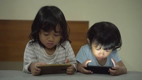 portrait of two toddler using mobile phone. kids focus with gadget