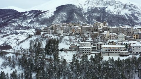 Aerial view of the beautiful snow-covered village of Opi with snow-capped mountains in the background. Opi is a comune and town in the province of L'Aquila in the Abruzzo region of central Italy..