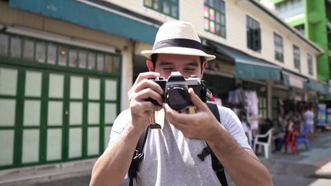 Asian man tourist photographer taking picture with camera in Khao San road Bangkok Thailand, slow motion effect