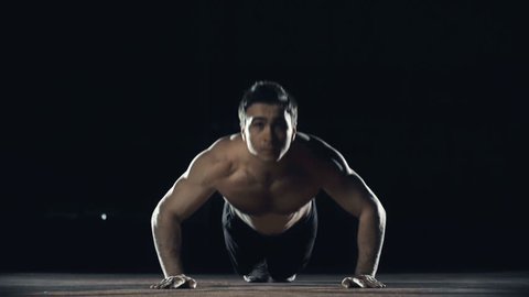 Front view of sportsman with naked torso performing explosive pushups clapping hands while in the air