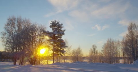 Sunset in the winter forest. Winter landscape on the lake. Frozen Lake Surrounded by Forest Covered with Snow at Winter.