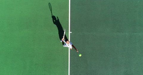 An Asian Tennis Player serves from above and celebrates serving an ace.