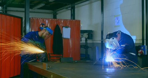 Time lapse of workers using grinder and welding torch in workshop. Attentive workers working together in workshop 
