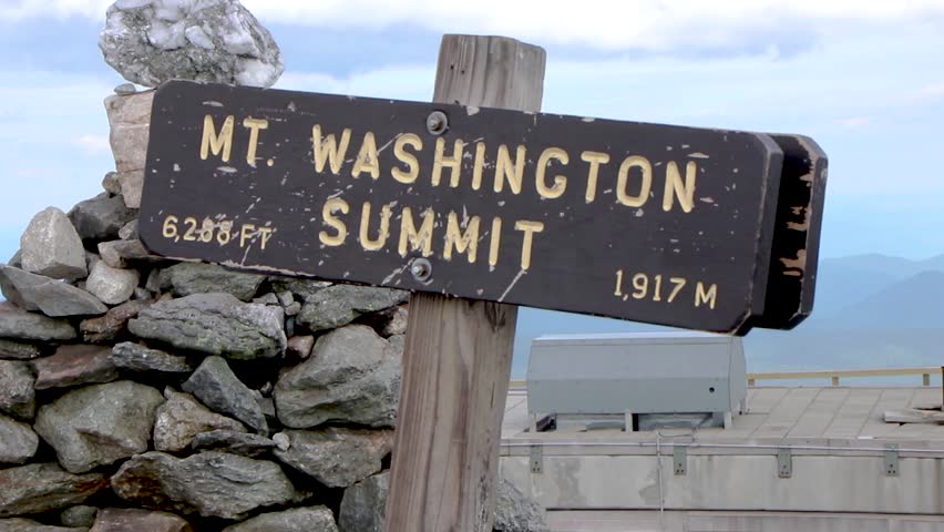 Video of the Mt. Washington Summit sign with a blue sky background and stacked pebbles