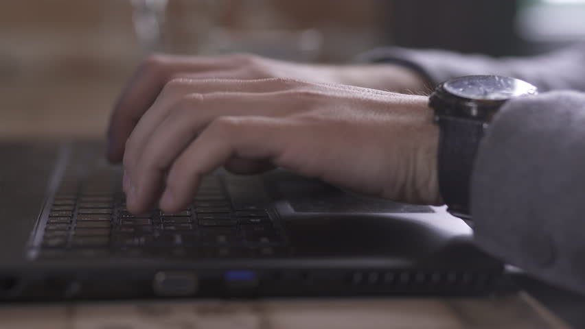 Businessman hands close up, young man typing on keyboard of black laptop, guy using computer for work in coffee bar, daylight reflection on the watch, glass of water in the blurred background, indoors | Shutterstock HD Video #1023138520