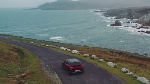 aerial view of red Toyota Auris car moving on beautiful curved coastal road. Ireland, Achill Island, 3rd of January 2019