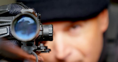 Front view close-up of Caucasian military soldier looking through riflescope during training at base. Soldier down on their position 