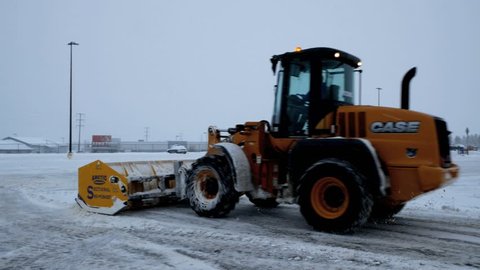 BEMIDJI, MN - DEC 27, 2018: Snow removal machine clearing a parking lot during a winter storm.