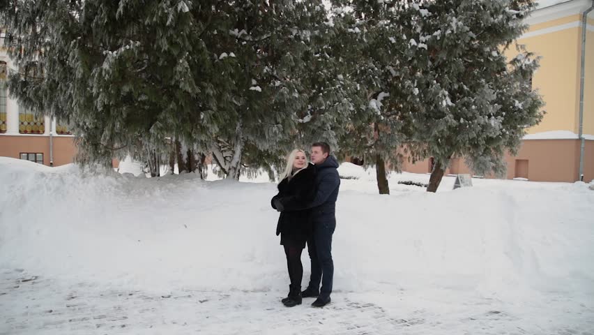 Beautiful young couple hugging and talking in a city winter park.