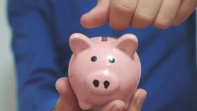 businessman man makes savings puts coins in a piggy bank. piggy bank business concept. slow motion video. saving money is an investment for the future. Banking investment and finance. hand is putting