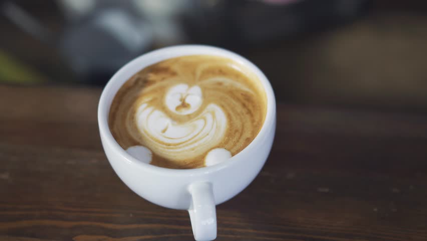 Hands of a bartender drawing with stick in a white cup of cappuccino. Process of making nice morning cappuccino coffee | Shutterstock HD Video #1023169756