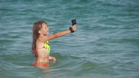 Child filming video in sea. Happy little girl using action camera on resort.