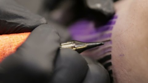Tattoo artist draw the line on skin of his client, macro view on the needle