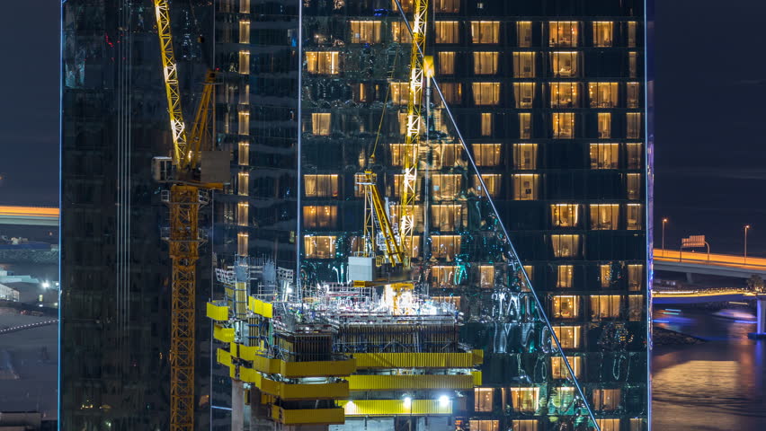Construction site with cranes. Building of skyscrapers. Aerial top view with many workers and glowing windows on background Royalty-Free Stock Footage #1023183640