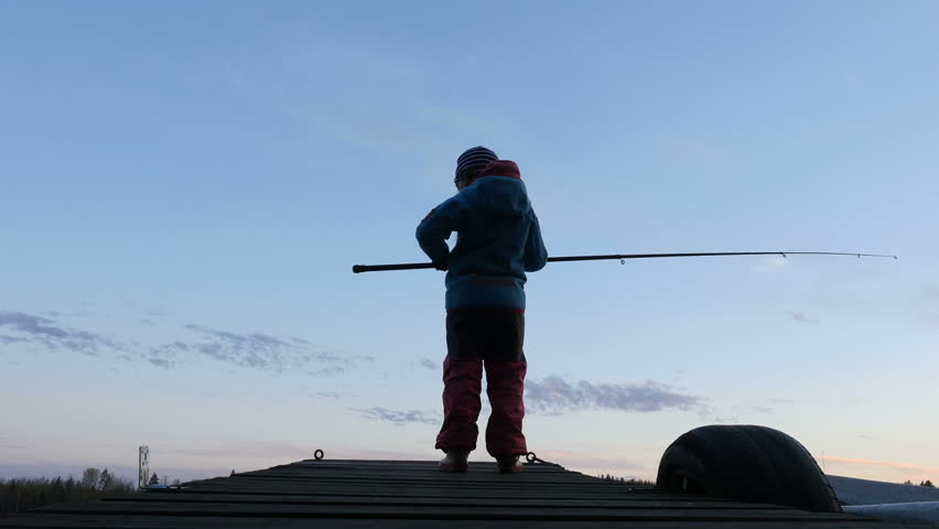 Kid fishing at dusk, silhouette of a little girl with rod fishing