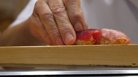 Skilled Japanese sushi chef prepare delicious nigiri at the restaurant, close up, filmed in 4K
