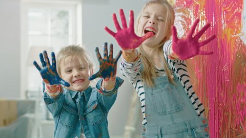 Two Fun Little Sisters Show Their Hands that are Dipped in Colorful Paint. They are Happy and Laugh. Sisterhood Goals. Redecoration at Home.