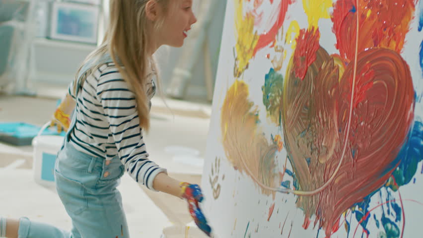 Happy Little Girl with Hands Dipped in Vivid Paint Draws Colorful Abstractions on the Wall. She is Having Fun and Laughs. Home is Being Renovated. Royalty-Free Stock Footage #1023188080